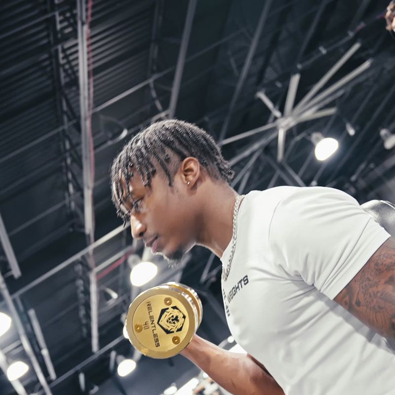 Damone doing a seated dumbbell curl in a Faith and Weights shirt